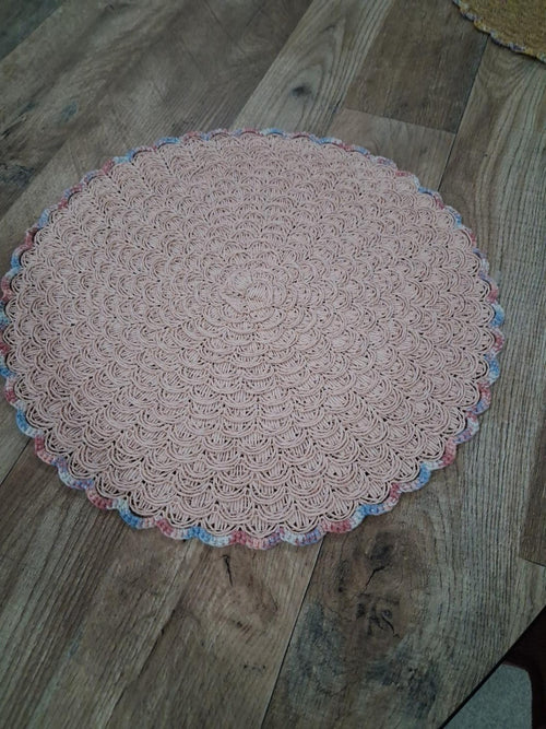 Fotografia real de base de mesa rosa-pálido com croché de conchas e bordadura multicolor